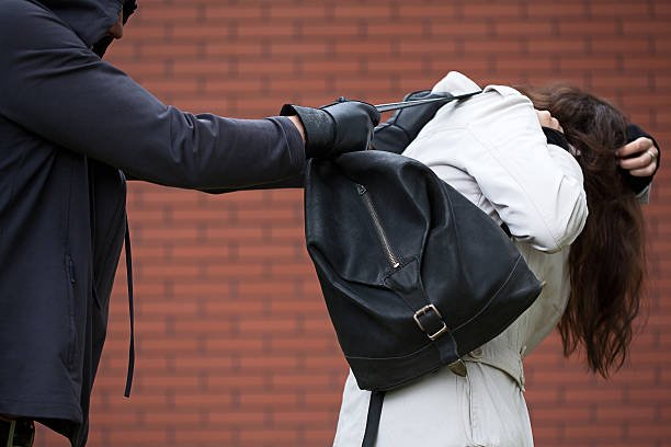 Dangerous masked man is assaulting a student to steal a anti theft backpack from a solo-traveller