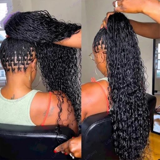 Stylist installing long braided wig with curly ends on woman, showing natural scalp design and high ponytail hairstyle for realistic protective look.